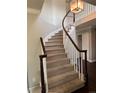 Elegant curved staircase with hardwood railing, carpeted steps, and a chandelier lighting the foyer at 11506 Greenbriar Ln, Parker, CO 80138