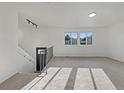 Clean, sunlit living room with neutral carpet, modern staircase, and large windows at 12238 Monroe Dr, Thornton, CO 80241