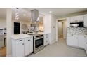 Modern kitchen with stainless steel appliances, white cabinets, and a stylish range hood at 2202 S Grape St, Denver, CO 80222