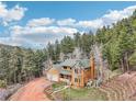 Stunning aerial view of the home nestled amongst a mature forest, on a beautifully landscaped lot at 13314 Spruce Creek Cir, Larkspur, CO 80118