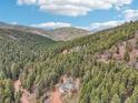Expansive aerial view of the home nestled amongst a mature forest on the side of a mountain at 13314 Spruce Creek Cir, Larkspur, CO 80118