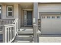 Inviting front porch with a gray door and stone accents, next to the garage at 9544 Pitkin St, Commerce City, CO 80022