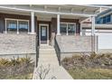 Inviting front porch with stylish columns, brick accents, and a charming entrance to the home at 1875 Hickory Ave, Erie, CO 80516