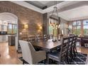 Elegant dining room featuring a brick accent wall, hardwood floors, and stylish lighting fixtures, great for gatherings at 858 Swandyke Dr, Castle Rock, CO 80108