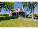 Inviting home with a spacious porch, brick accents, and lush greenery at 14447 Madison St, Thornton, CO 80602