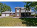 Two-story home featuring a brick facade, an attached garage, a front porch and a well-maintained lawn at 14447 Madison St, Thornton, CO 80602
