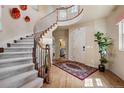 Elegant foyer features a curved staircase with iron railings, hardwood floors, and decorative wall art at 5192 Sedona Dr, Parker, CO 80134