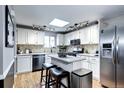 Bright kitchen with skylight, featuring white cabinetry, granite countertops, stainless steel appliances and a center island at 715 Zang St, Lakewood, CO 80401