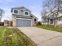 A two-story home featuring gray siding, stone accents, a two-car garage, and a well-kept front lawn at 4010 E 129Th Way, Thornton, CO 80241
