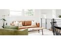 Bright open living room with a green chair, brown leather couch, and a coffee table at 1617 S Quitman St, Denver, CO 80219