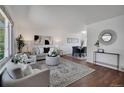 Bright living room featuring hardwood floors, modern decor, and a view into the dining area at 9386 W Geddes Pl, Littleton, CO 80128