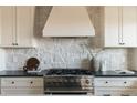 Close-up of a modern range against a stone backsplash, surrounded by white cabinetry and black countertops at 353 Columbine Ave, Broomfield, CO 80020