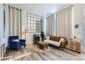 Stylish living room featuring a blue armchair, leather sofa, wood floors, and large wall mirror at 19827 E Prentice Ave, Centennial, CO 80015