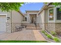 Inviting home entrance featuring a stone facade, seating, and meticulous landscaping at 1051 Bramblewood Dr, Castle Pines, CO 80108