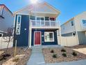 Charming two-story home featuring a balcony, a red front door, and low-maintenance landscaping at 45016 Sunflower Ln, Bennett, CO 80102