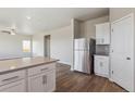 Open-concept kitchen featuring a large island, stainless steel refrigerator, and adjacent living space at 48230 Shetland Dr, Bennett, CO 80102