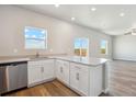 Bright, open kitchen with a large island, stainless steel dishwasher, and views of the outdoors at 48230 Shetland Dr, Bennett, CO 80102