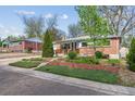Charming ranch-style home with a brick exterior, a well-manicured lawn, and mature trees at 6882 Moore St, Arvada, CO 80004