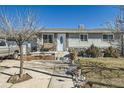 Inviting single story home featuring stone accents, front porch seating, and a well-manicured front yard at 7310 Carnation Pl, Commerce City, CO 80022