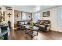 Cozy living room with elegant leather furniture, dark laminate floors and charming decor at 7310 Carnation Pl, Commerce City, CO 80022