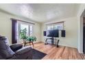 Relaxing living room with hardwood floors, large window, and entertainment center at 6991 Warren Dr, Denver, CO 80221