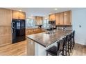 Kitchen island offers bar seating, wood cabinets, and stylish countertops with a black refrigerator at 3150 W Stanford Ave, Englewood, CO 80110