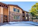 Tan and stone townhouse with a two-car garage and snowy front yard at 9876 W Freiburg Dr # G, Littleton, CO 80127