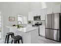 Modern kitchen featuring white cabinets, stainless steel appliances, a breakfast bar, and sleek countertops at 17634 E Ohio Cir, Aurora, CO 80017