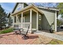 Inviting covered porch with seating on a brick patio provides a warm welcome to the home at 6701 W Yale Ave, Lakewood, CO 80227