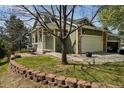 Home exterior with a two-car garage, stone accents, and a charming brick-paved patio at 6701 W Yale Ave, Lakewood, CO 80227