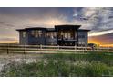 Backyard of large modern house with fence and grassy field at sunset at 8868 Geyser Peak Way, Parker, CO 80138
