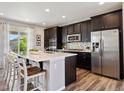 Modern kitchen featuring a center island, stainless steel appliances, dark cabinets, and a stylish backsplash at 16268 Mount Silverheels Way, Broomfield, CO 80023