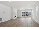 Open living room featuring wood floors, a modern fireplace, and sliding glass doors at 1306 Sienna Peak Cir, Erie, CO 80516