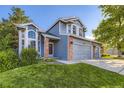 Two-story home featuring a three-car garage, blue siding, brick accents, and lush green lawn at 5645 S Himalaya Way, Centennial, CO 80015