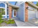 Home featuring a red front door, brick accents, blue siding, and manicured landscaping at 5645 S Himalaya Way, Centennial, CO 80015