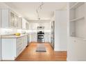 Open kitchen featuring stainless steel appliances, white cabinets, and wood flooring at 695 S Alton Way # 9C, Denver, CO 80247