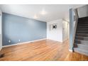 Spacious living room with hardwood floors, light blue accent wall, and staircase to upper floor at 6920 W 48Th Ave, Wheat Ridge, CO 80033