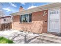 Close-up of brick home's front entrance, featuring a white door and well-manicured lawn at 10878 Patterson Ct, Northglenn, CO 80234