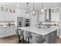 Bright kitchen featuring white cabinets, a gray tile backsplash, stainless steel appliances, and a large island with seating at 21102 E Stanford Dr, Aurora, CO 80015