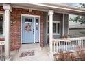 Inviting front porch with a powder blue door and fresh wreath offering a cozy seating area at 49 Dawn Heath Cir, Littleton, CO 80127