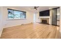 Bright living room featuring hardwood floors, fireplace, large windows, and a ceiling fan at 4244 W Monmouth Ave, Littleton, CO 80123