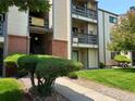 Close up view of a tan condo building showing the front entrance, stairwell, and nicely kept lawn at 539 Wright St # 203, Lakewood, CO 80228