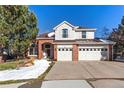 Two-story brick home with attached two-car garage and landscaped front yard at 317 Ingleton Ct, Castle Pines, CO 80108