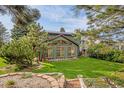 View of the expansive backyard with lush lawn, mature trees, and a charming brick-lined garden at 7655 S Olive Cir, Centennial, CO 80112
