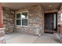 Inviting front porch with stone detailing and a secure, dark wood front door at 5131 Delphinium Cir, Brighton, CO 80601