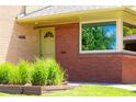 Close-up of the brick house showing the front door and surrounding landscaping at 6600 E 4Th Ave, Denver, CO 80220