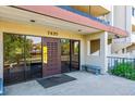 Building entrance with glass doors, bench, address number and overhead lighting at 7420 E Quincy Ave # 304, Denver, CO 80237