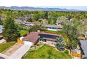 Aerial view of a house with solar panels, a fenced yard, and lush green surroundings at 11715 W 30Th Pl, Lakewood, CO 80215