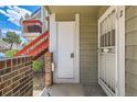 Condo front door with exterior brick and painted wood detailing and a secured screen door at 909 S Dawson Way # 2, Aurora, CO 80012