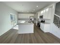 Modern kitchen featuring white cabinets, stainless steel appliances, a central island, and sliding door access to outside at 5546 Inland Ave, Firestone, CO 80504